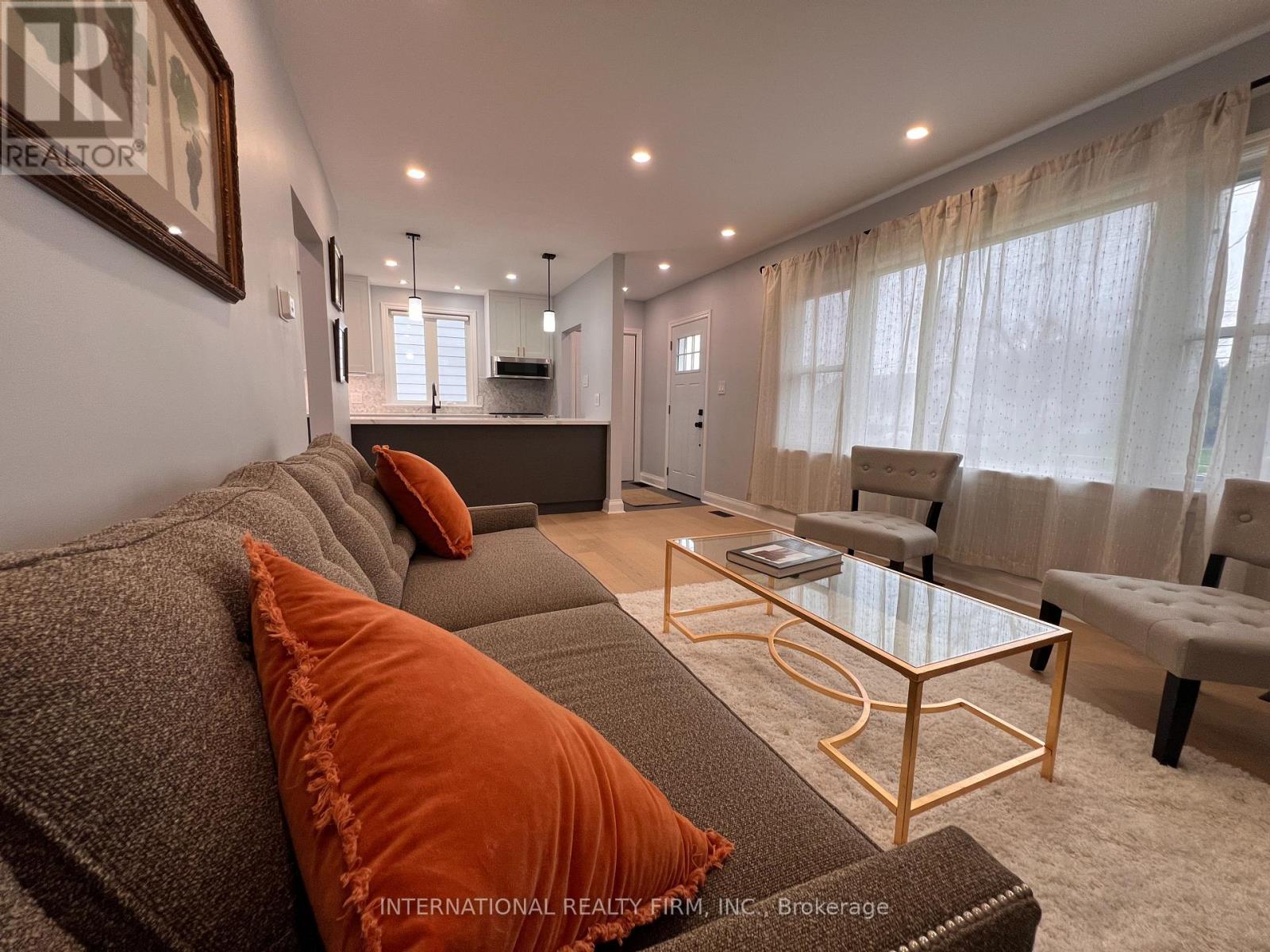 A living room with a grey couch and orange pillows.