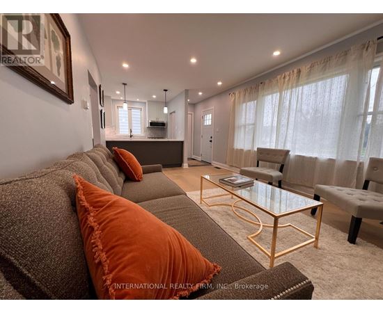 A living room with a grey couch and orange pillows.