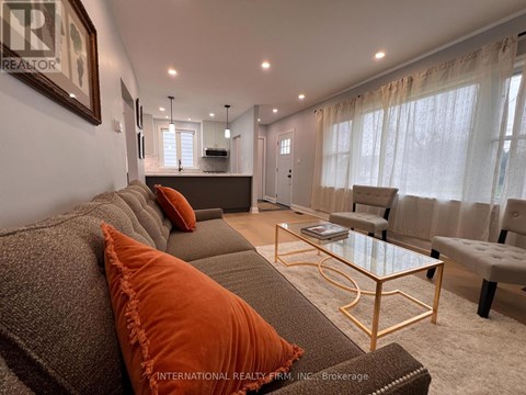 A living room with a grey couch and orange pillows.