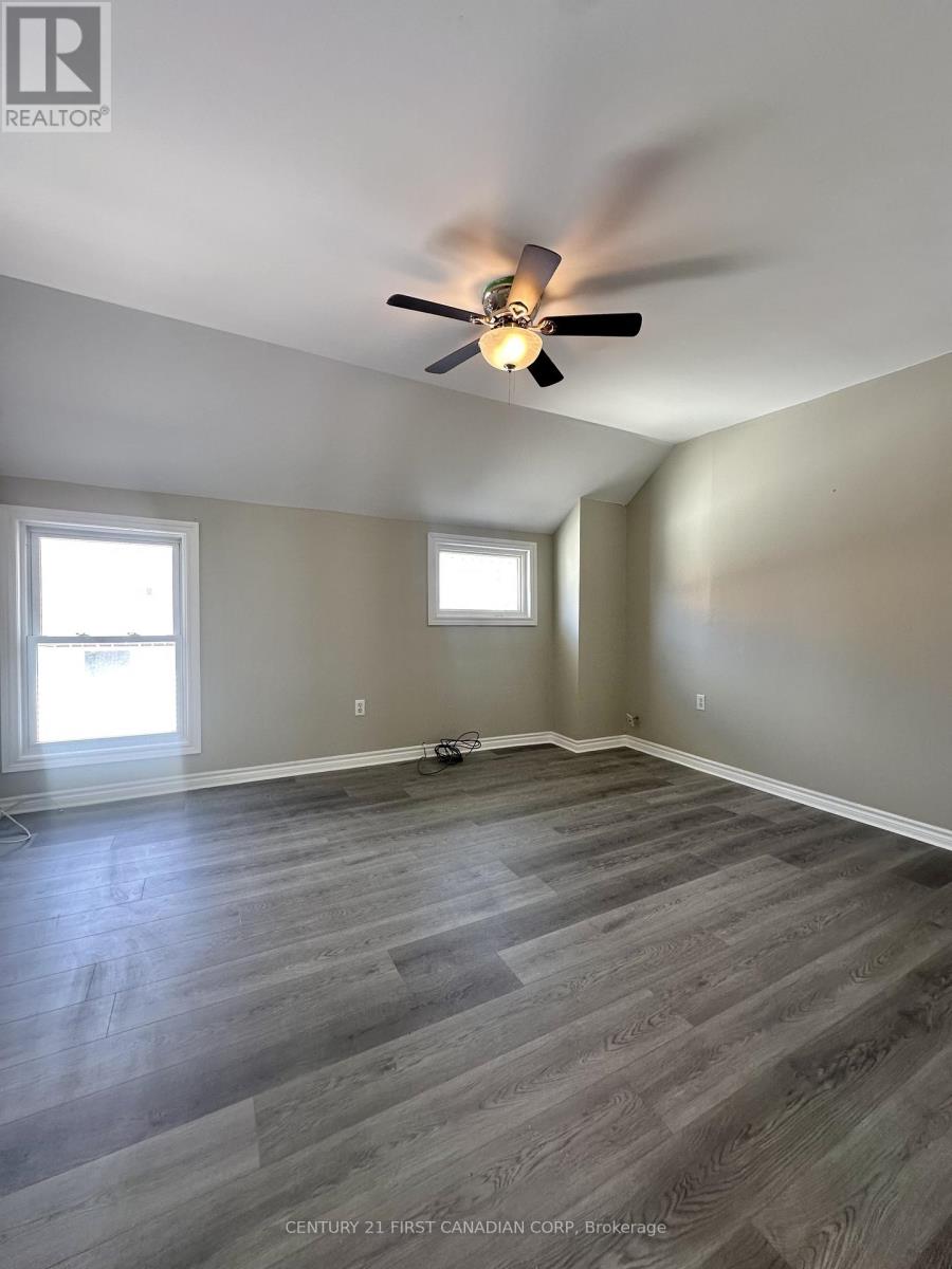 A room with a ceiling fan and two windows.