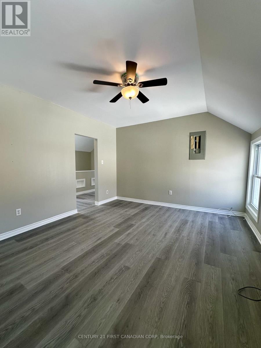 A room with a ceiling fan and wood flooring.