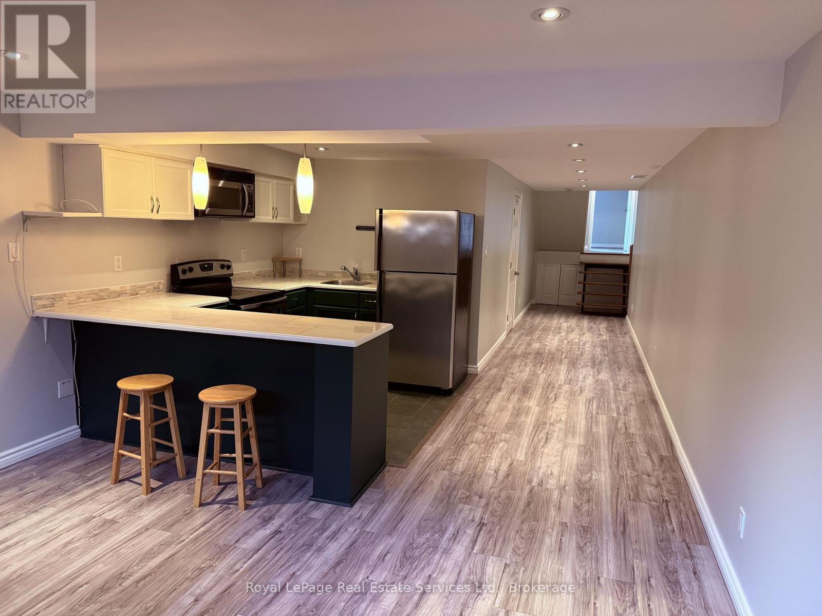 A kitchen with a bar and stools is shown in this image.