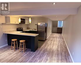 A kitchen with a bar and stools is shown in this image.