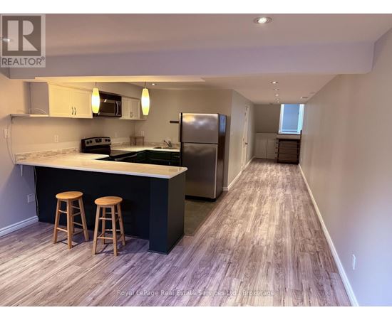 A kitchen with a bar and stools is shown in this image.