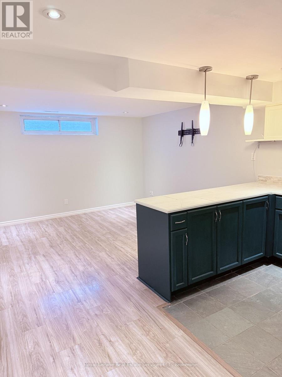 A kitchen with dark green cabinets and light wooden flooring.