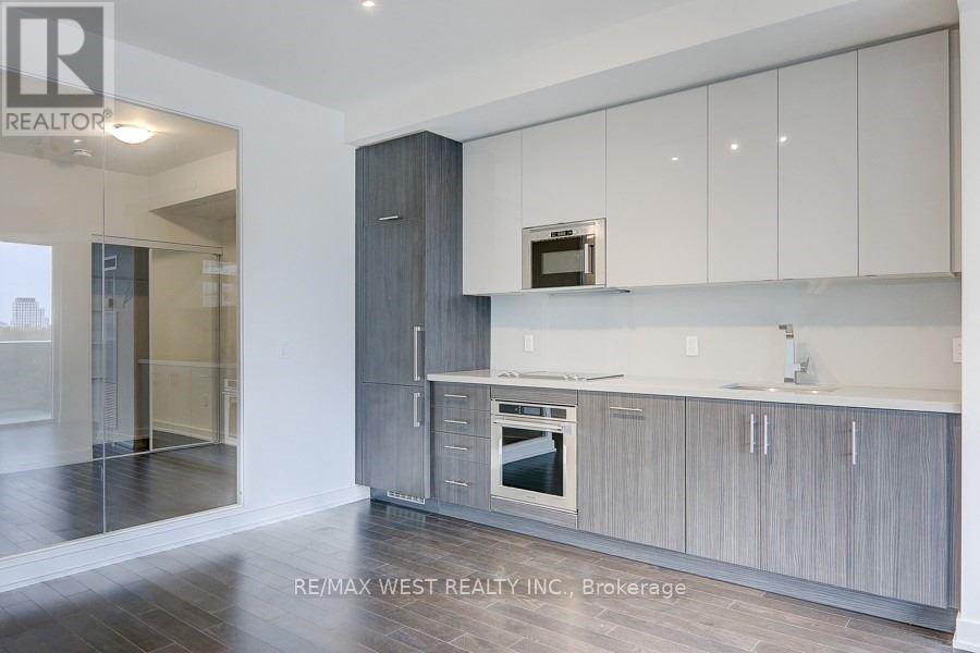 A modern kitchen with white cabinets and a wooden floor.