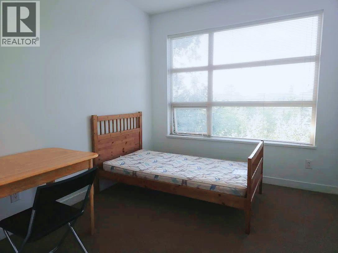 A bedroom with a bed, desk, and chair.
