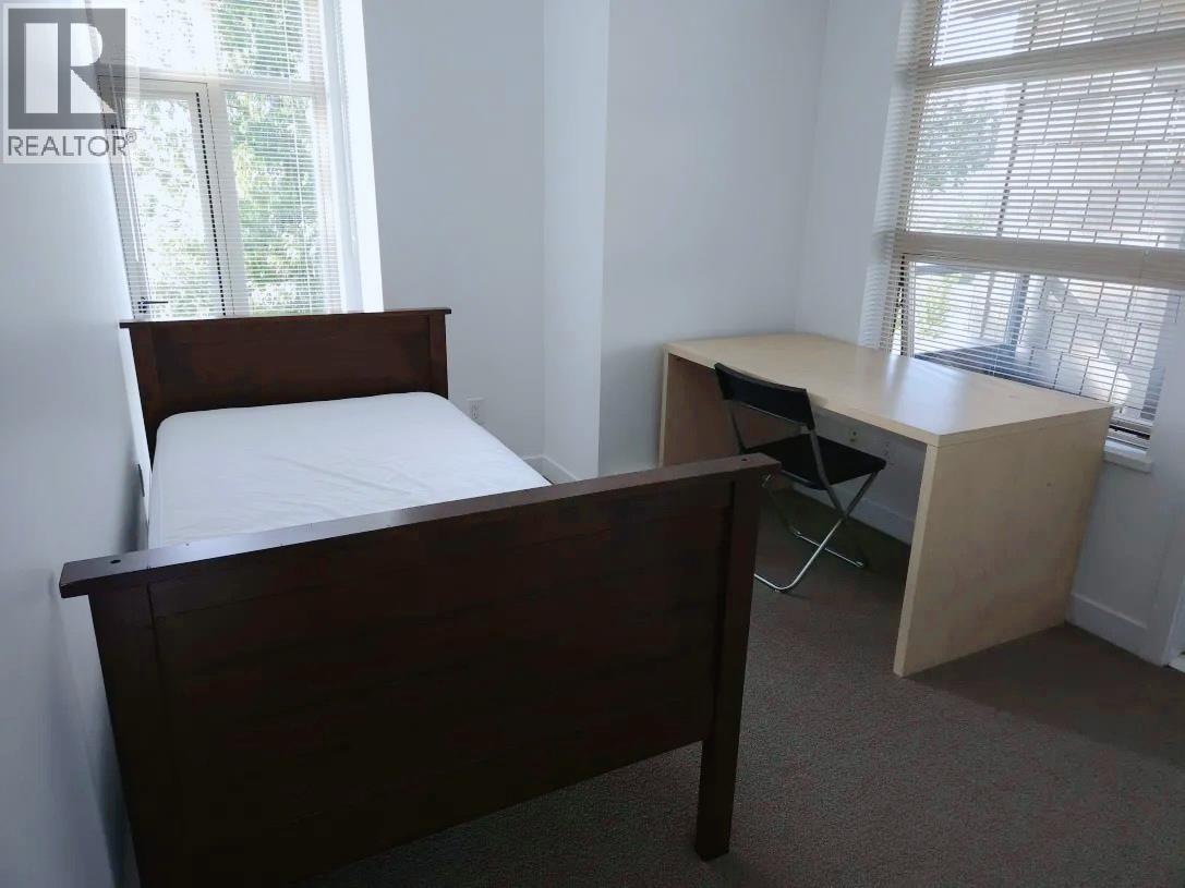 A bedroom with a bed, desk, and chair.