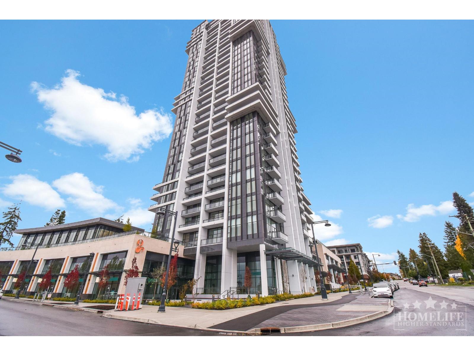 A tall building with a curved facade stands in front of a clear blue sky.