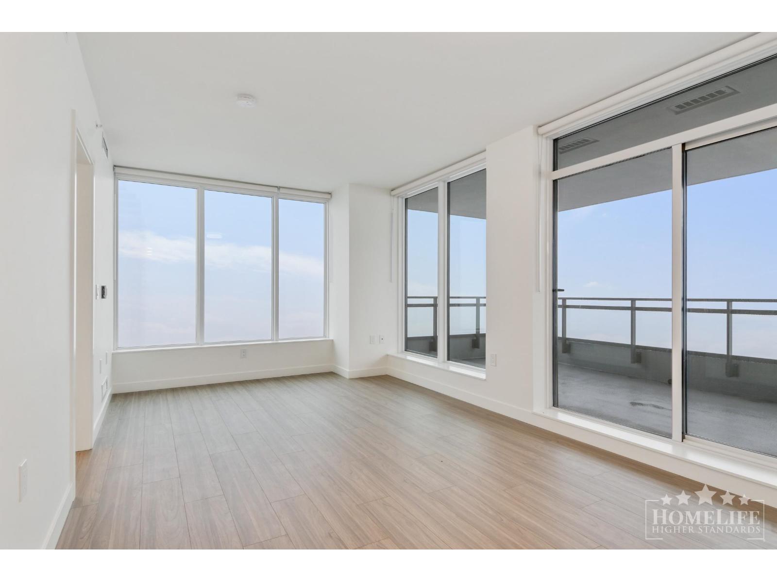 A spacious room with wooden floors and large windows overlooking the ocean.