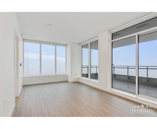 A spacious room with wooden floors and large windows overlooking the ocean.