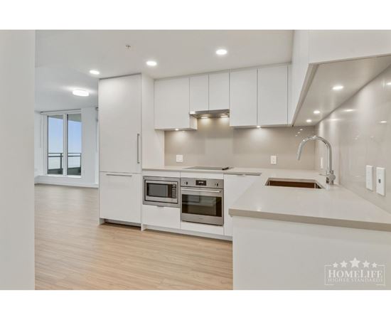 A modern kitchen with white cabinets and stainless steel appliances.