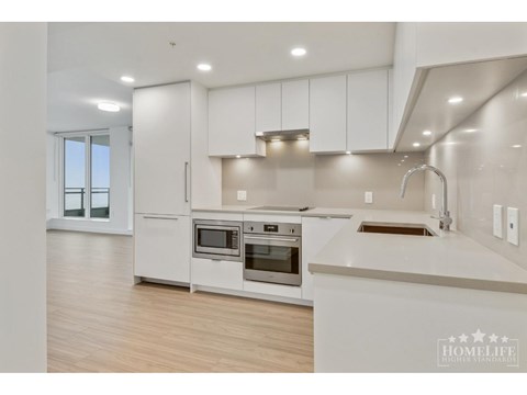 A modern kitchen with white cabinets and stainless steel appliances.