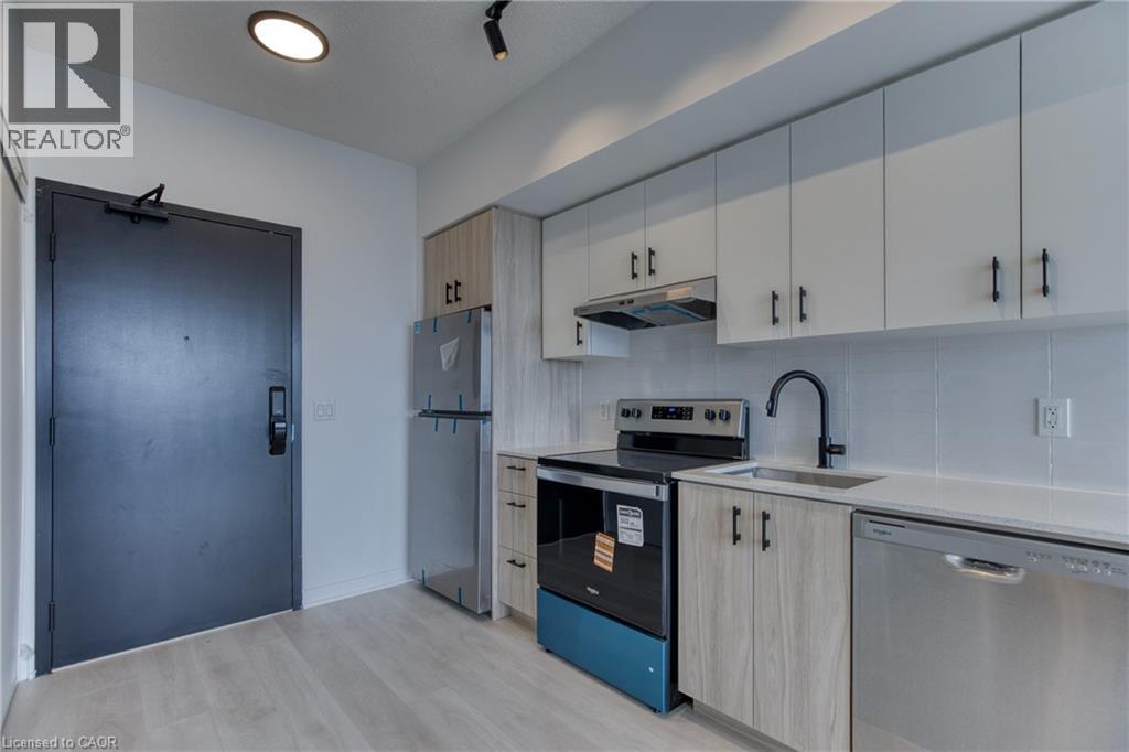 A modern kitchen with a black door, a stove, and a dishwasher.