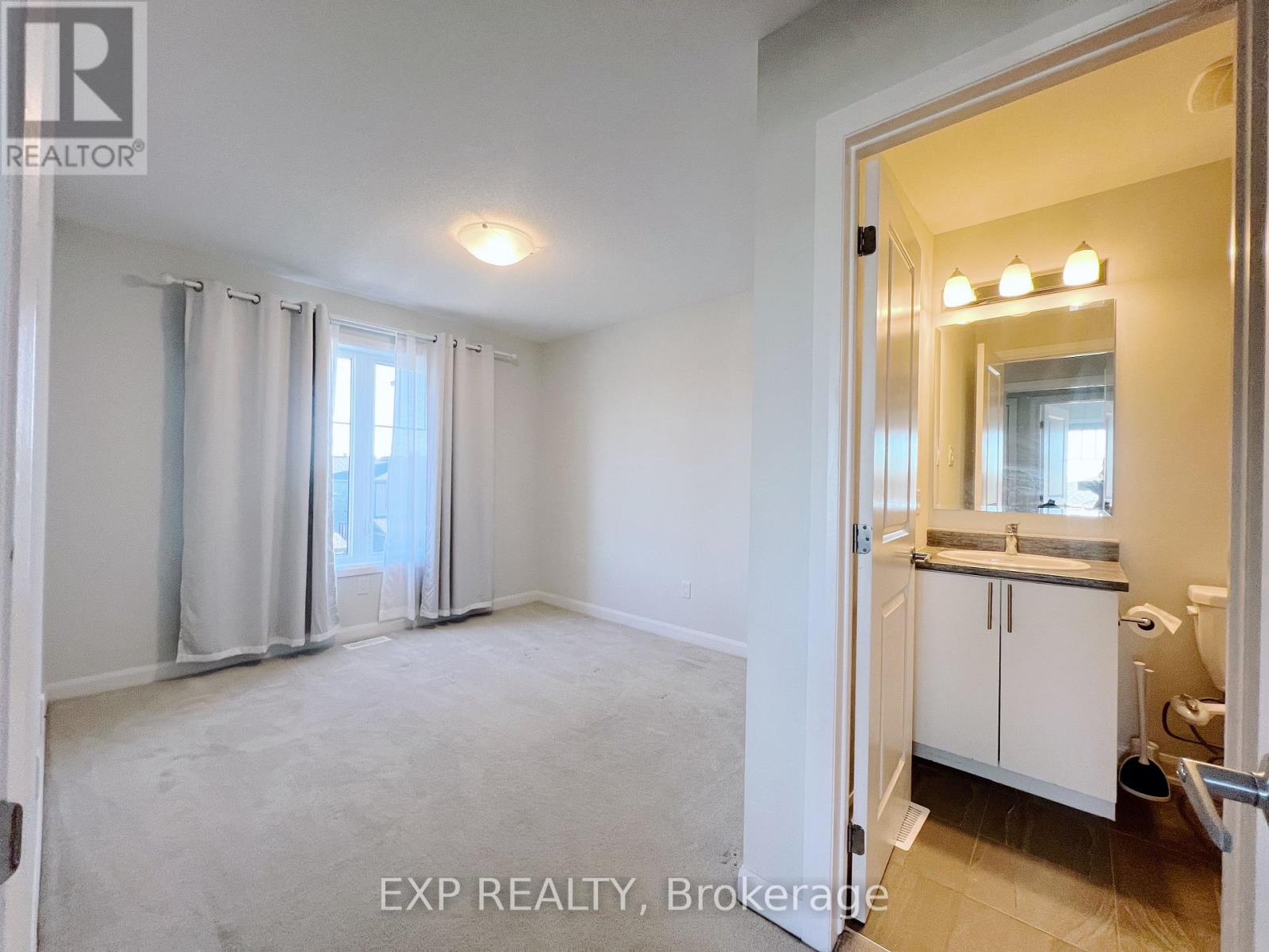 A white bedroom with a bathroom visible through the open door.