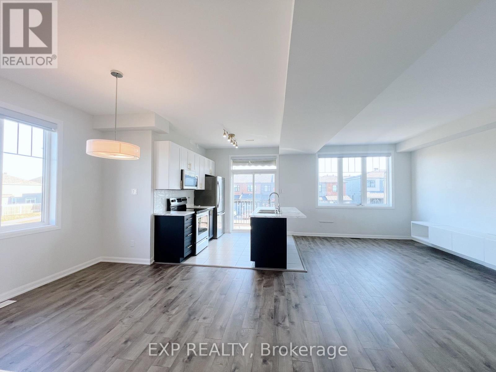 A spacious, empty room with wood flooring and white walls.