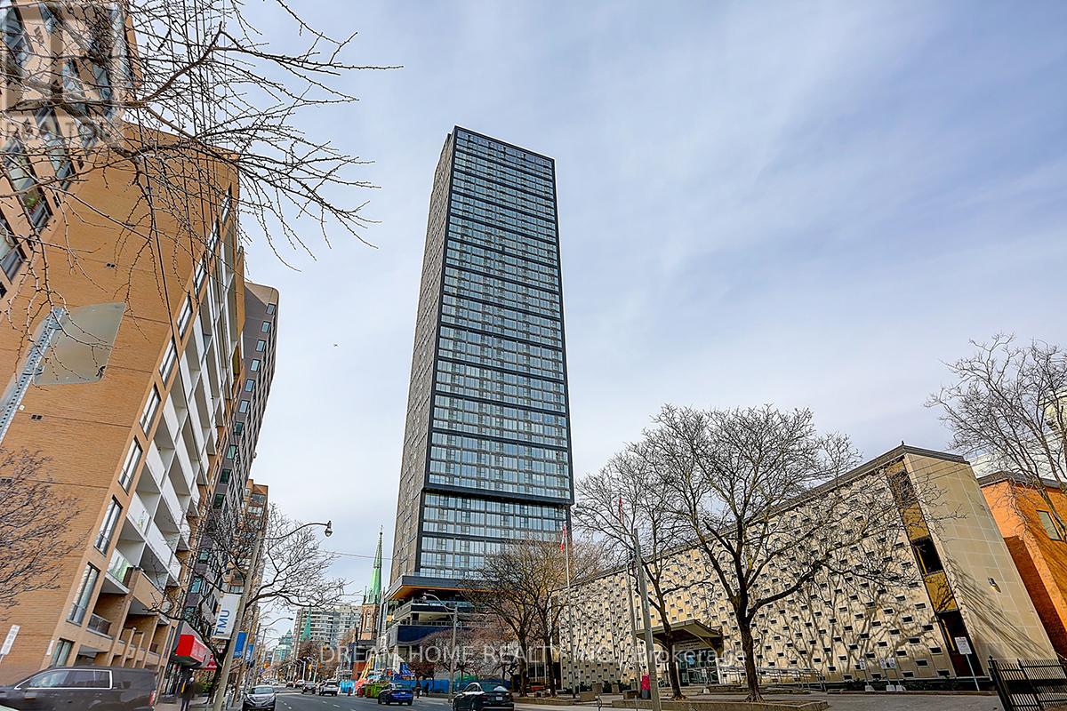 A tall glass building stands in the middle of a city street.