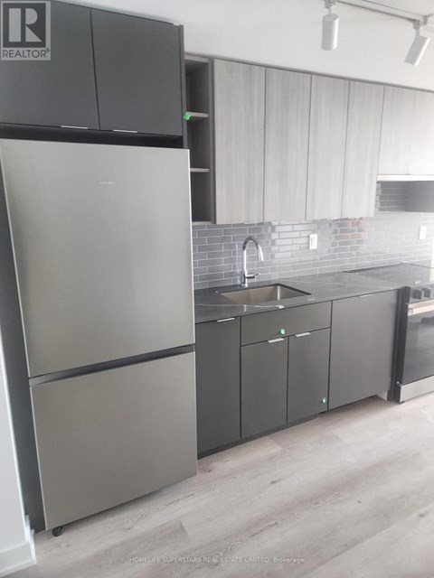 A modern kitchen with a stainless steel refrigerator and cabinets.