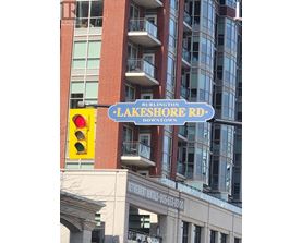 A red and white street sign for Burlington Lakeshore Rd. is in front of a building.