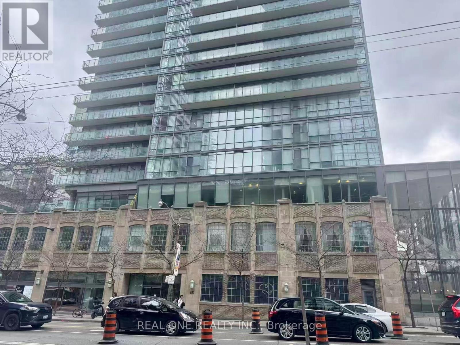 A black car with the text REALTOR on the side is parked in front of a building.