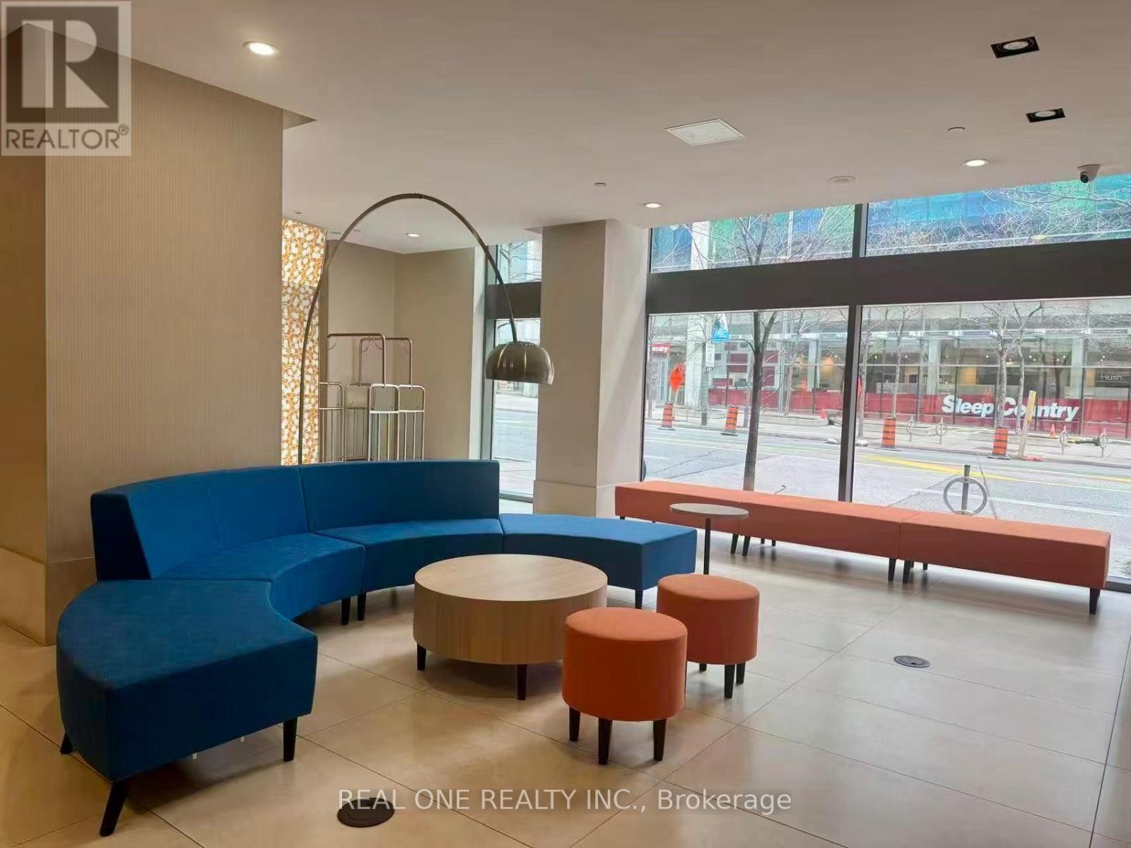 A blue couch and orange ottoman are in a room with a large window.