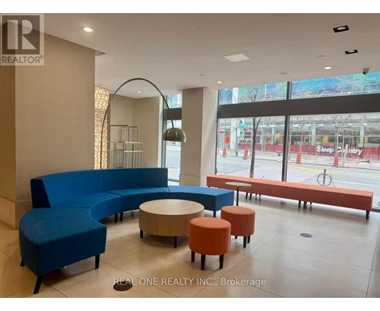 A blue couch and orange ottoman are in a room with a large window.