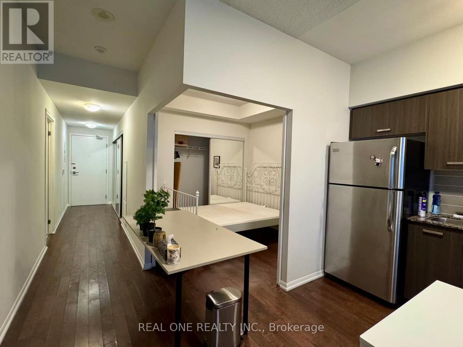 A kitchen with a refrigerator, table and chairs.