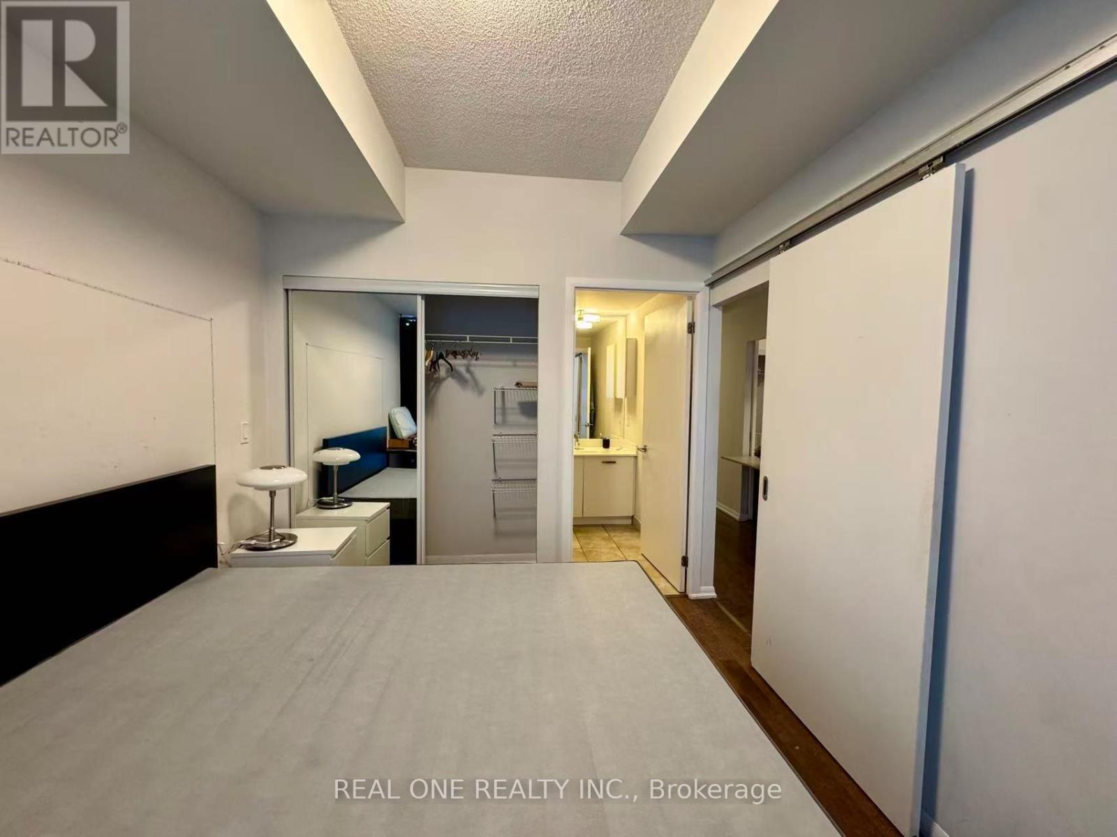 A bedroom with a bed, a desk, and a mirror.