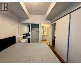 A bedroom with a bed, a desk, and a mirror.