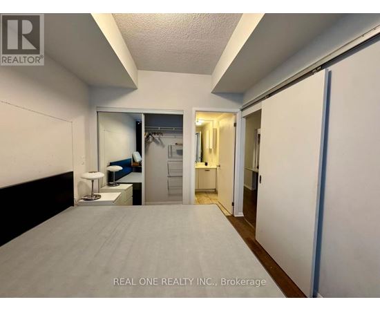 A bedroom with a bed, a desk, and a mirror.