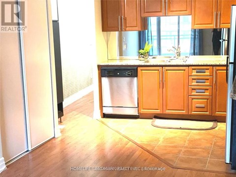 A kitchen with wooden cabinets and a black fridge.