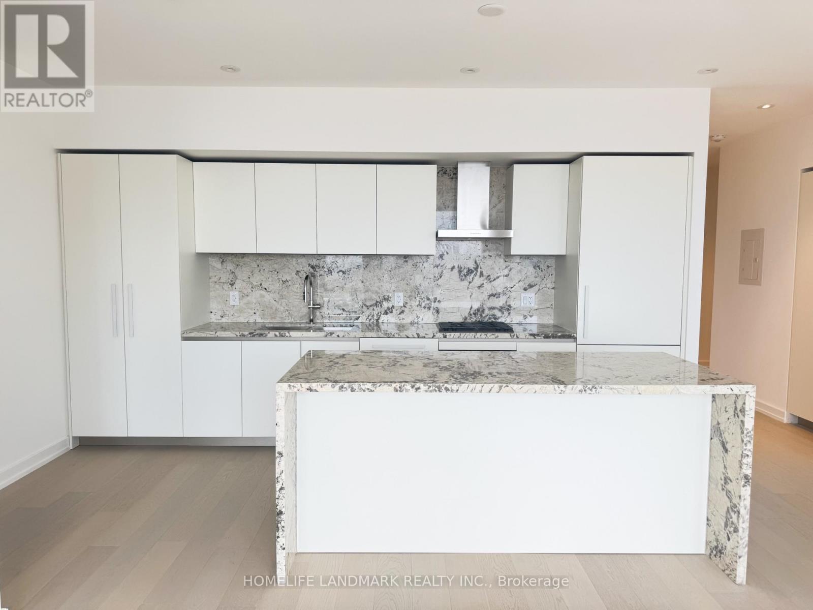 A kitchen with white cabinets and a marble island.
