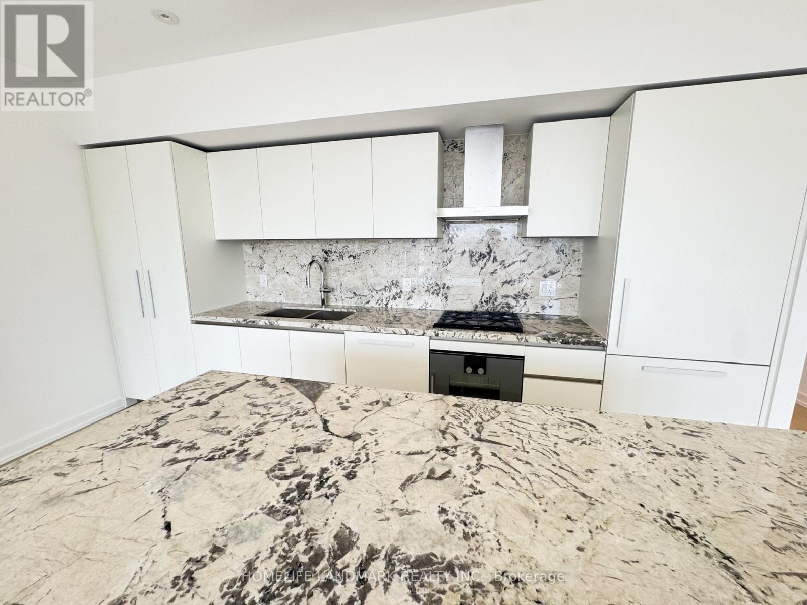 A kitchen with a marble counter top and white cabinets.