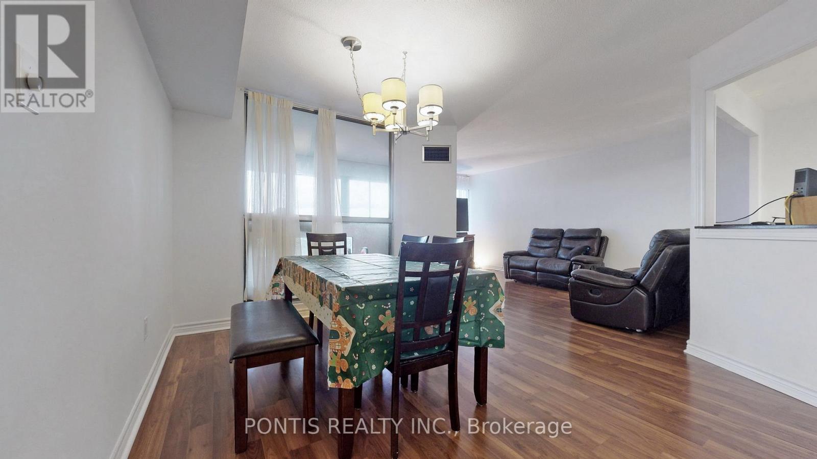 A dining room with a table set for two and chairs with a floral tablecloth.