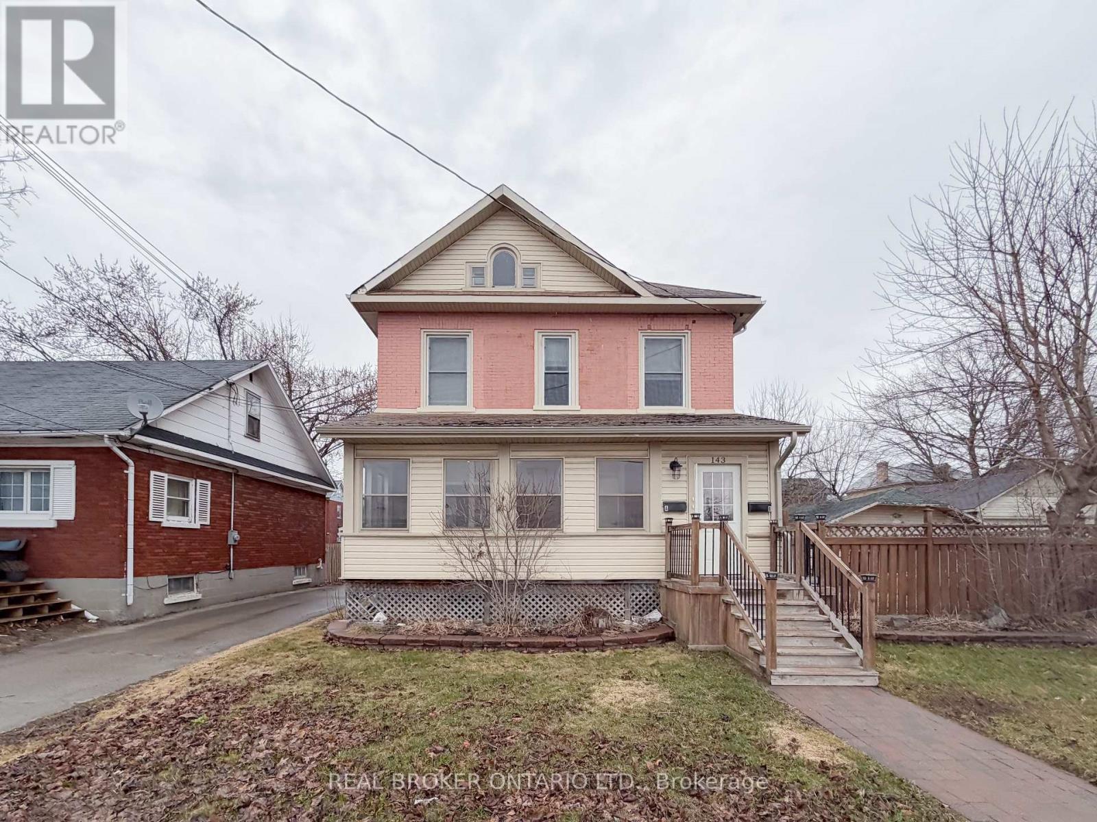 A two-story house with a red brick exterior and a beige siding.