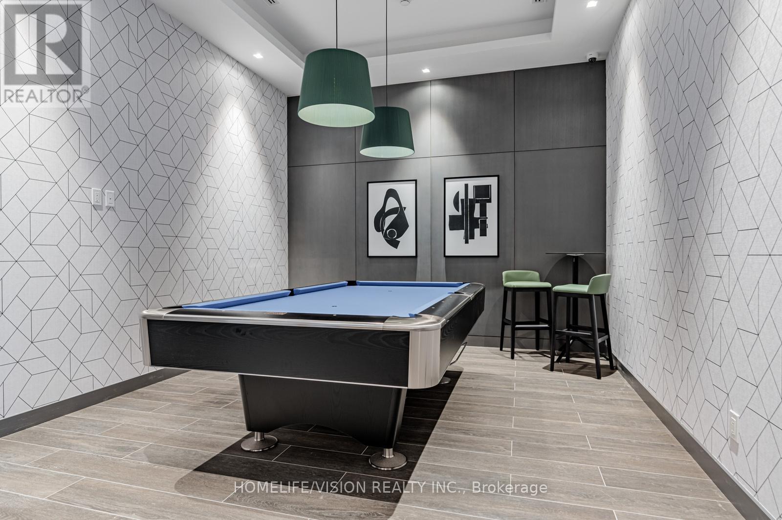 A pool table in a room with a grey wallpaper and two green lampshades.