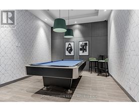 A pool table in a room with a grey wallpaper and two green lampshades.