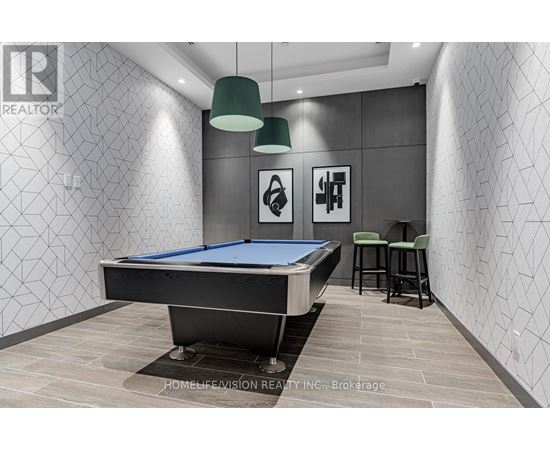 A pool table in a room with a grey wallpaper and two green lampshades.