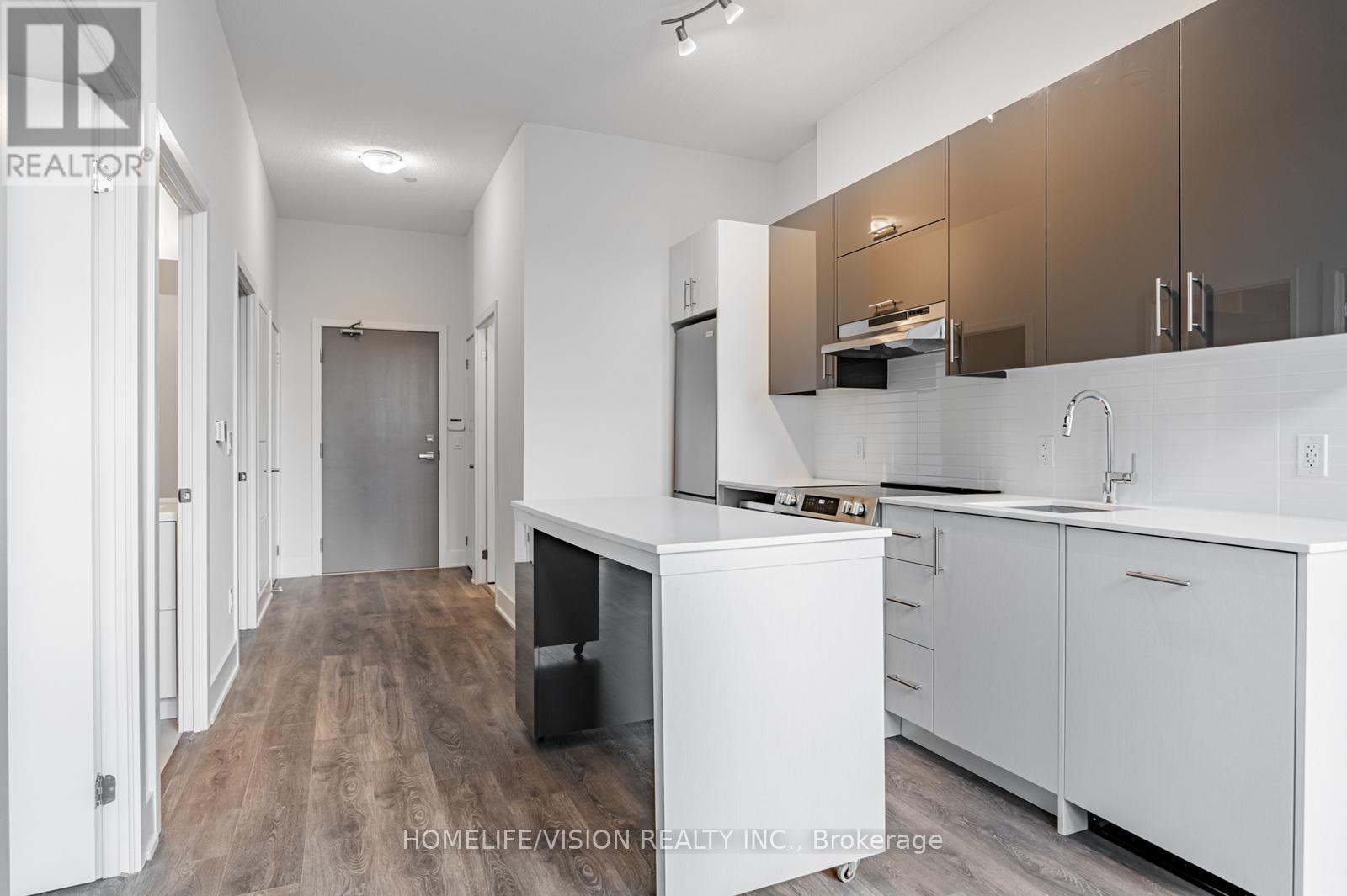 A modern kitchen with white cabinets and a wooden floor.