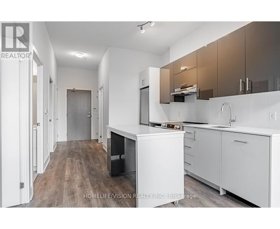 A modern kitchen with white cabinets and a wooden floor.