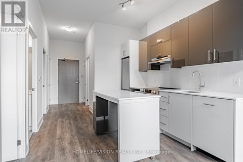 A modern kitchen with white cabinets and a wooden floor.