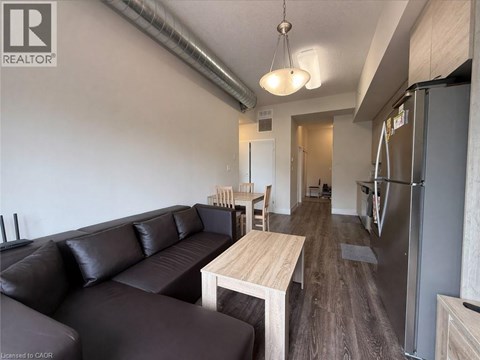 A living room with a black leather couch and a wooden table.