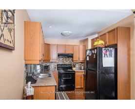 A kitchen with wooden cabinets and a black refrigerator.