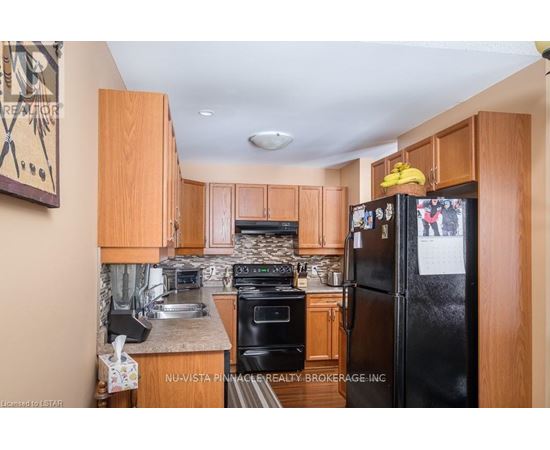 A kitchen with wooden cabinets and a black refrigerator.