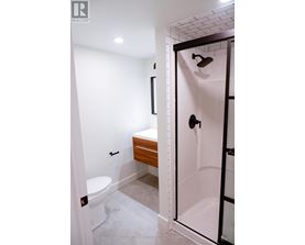 A white bathroom with a toilet and a walk in shower.