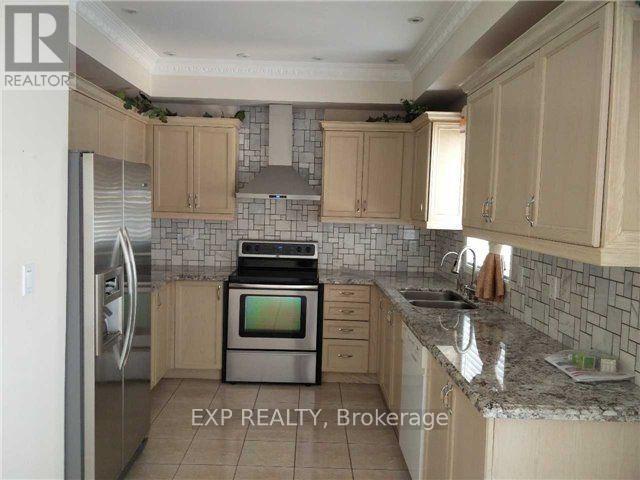 A kitchen with a refrigerator, oven, and sink.
