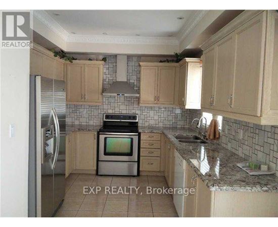 A kitchen with a refrigerator, oven, and sink.
