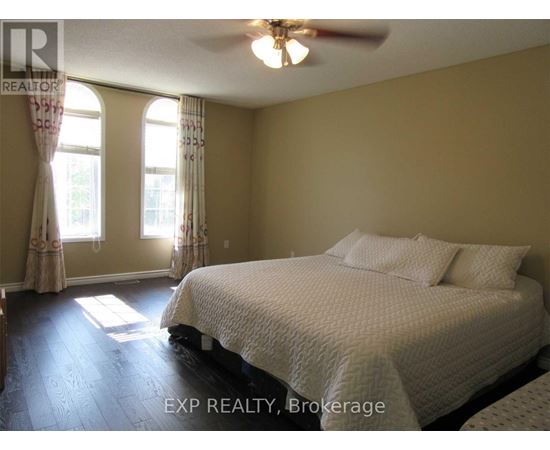 A bedroom with a bed, a ceiling fan, and two windows.