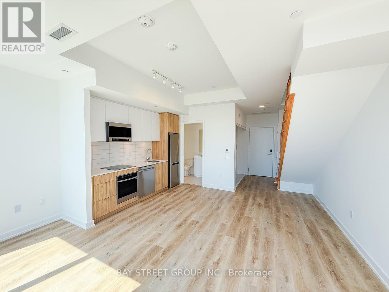 A spacious, empty apartment with wood flooring and white walls is on the market.