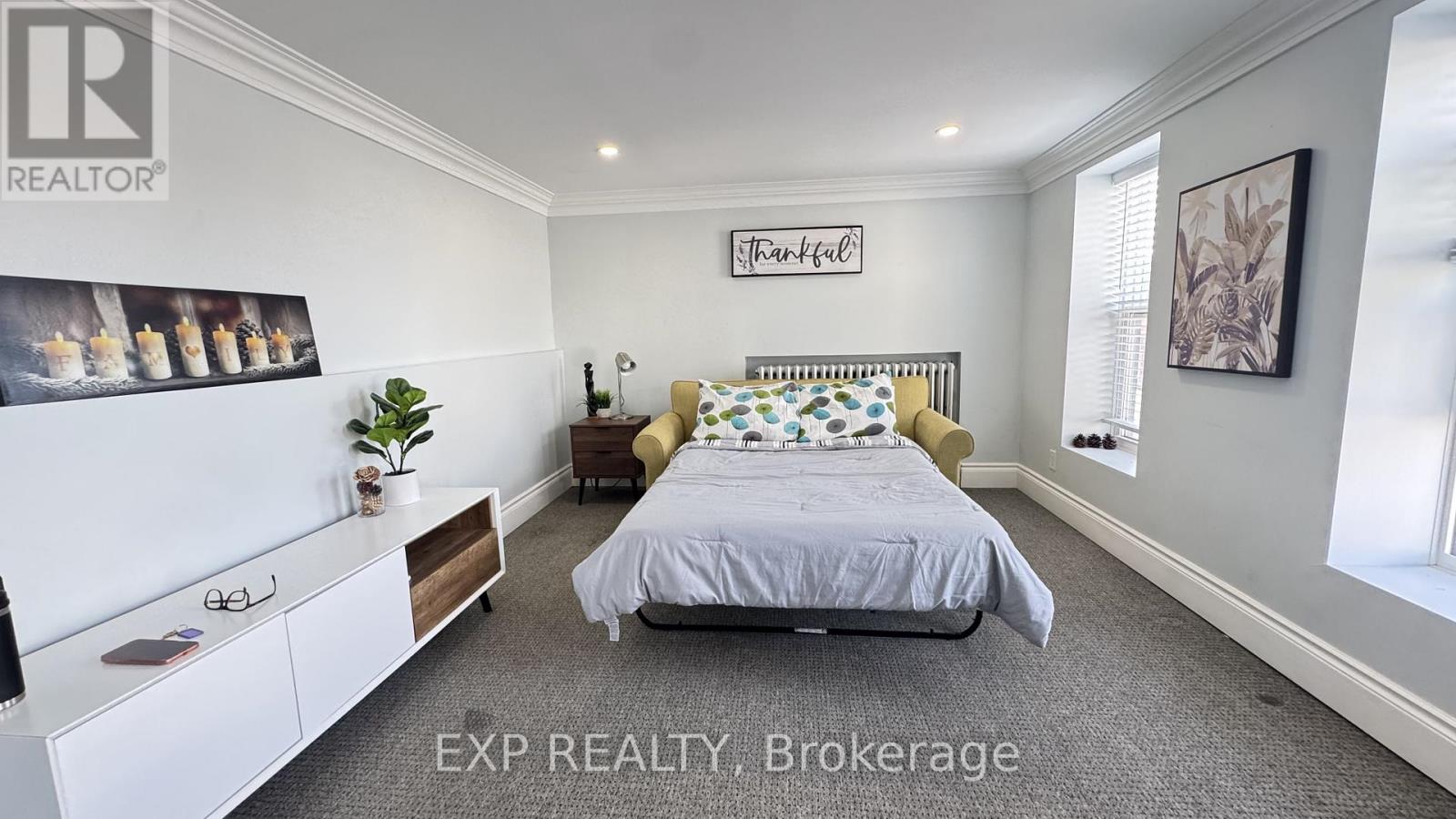 A bedroom with a bed, nightstand, and a wall-mounted shelf with a plant on it.